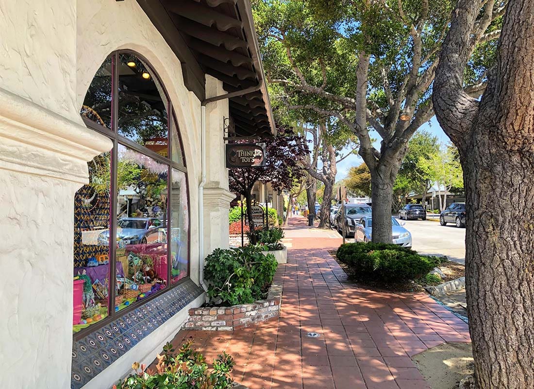 Contact - Closeup View of a Boutique Store Next to a Paved Walkway with Green Foliage in Downtown Carmel California